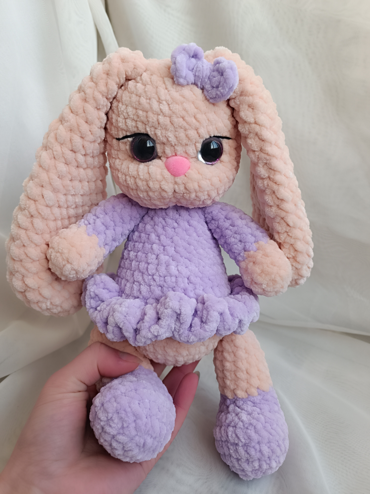 A crocheted rabbit in a purple dress with long ears